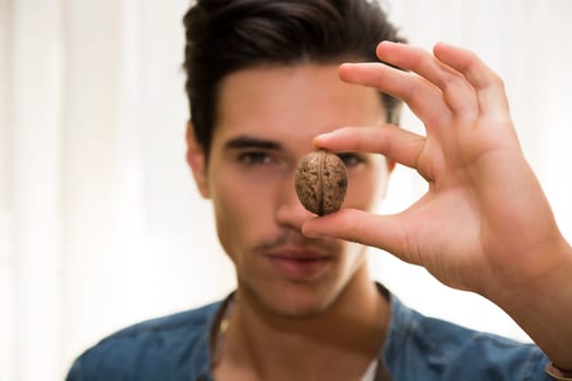 Young man holding a large delicious nut in his hand, focus to the fruit