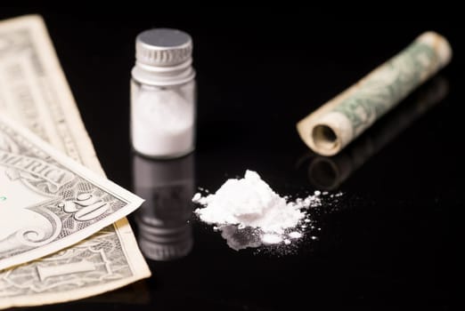 cocaine or other illegal drugs that are sniffed by means of a tube, isolated on black glossy background