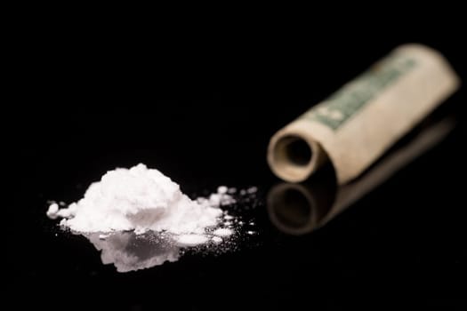 cocaine or other illegal drugs that are sniffed by means of a tube, isolated on black glossy background