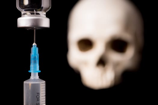medical vials, syringe and blurry skull isolated on black background