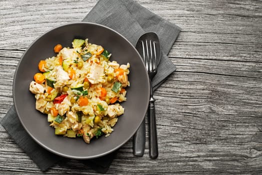 Risotto with chicken and vegetables served on wooden table