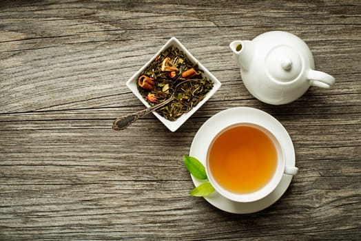 Cup of tea with dry green tea collection on wooden table
