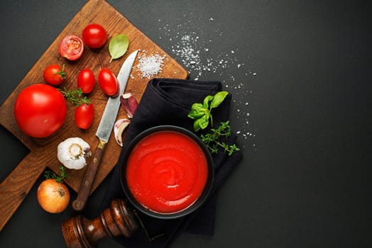Fresh ingredients for cooking tomato sauce or soup on black background place for text. Vegan food vegetarian and healthy cooking concept.