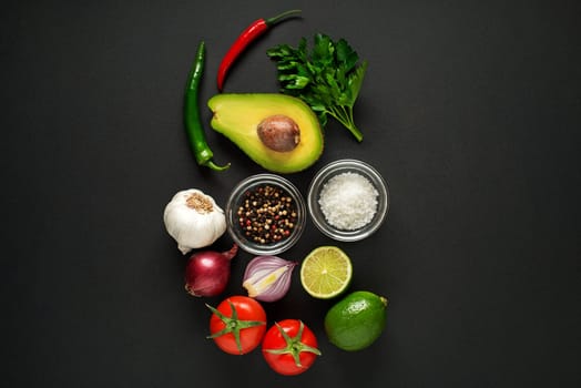 Fresh ingredients with avocado for guacamole sauce on black background