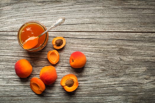 Apricot jam in a glass bowl with fruit around
