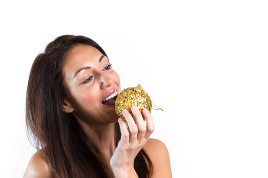 Portrait of beautiful girl want to eat a christmas ball. The young woman smiles. Ideal for Christmas or New Year holidays.