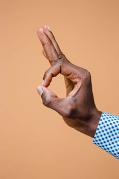 Hand showing OK sign isolated on brown background. Close-up of positive gesture, like, agreement, accept concept concept