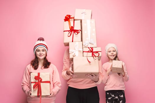 Father and mother give gifts to little daughter at pink studio background