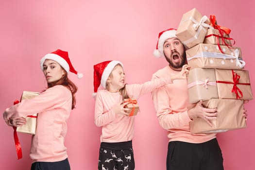 Father and mother give gifts to little daughter at pink studio background