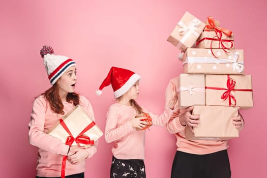 Father and mother give gifts to little daughter at pink studio background