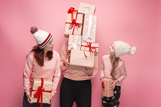 Father and mother give gifts to little daughter at pink studio background