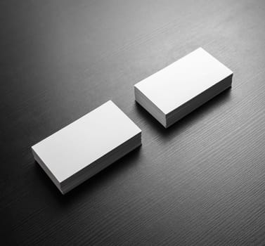 Photo of blank white business cards on black wooden table background. Template for ID. Mockup for branding identity.