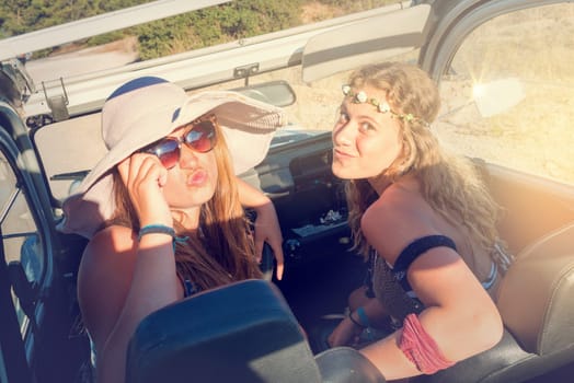 Retro image of girl friends in a car at sunset