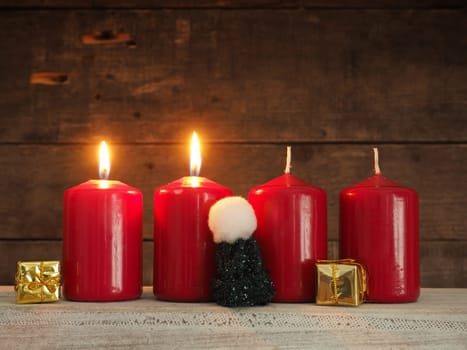 Four red Advent candles on a rustic wooden background, two candles burning, scond Advent, Christmas concept background