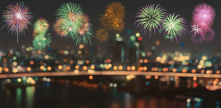 Colorful fireworks on skyline background with blurred city night illuminated lights bokeh
