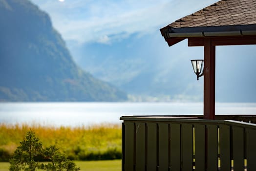 House at lake, mountains and blue sky in background. Scandinavia, Europe travel.