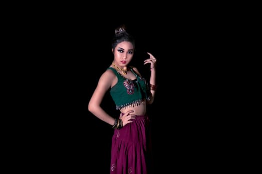 Portrait of asian belly dancer posing in colorful cloth over black background