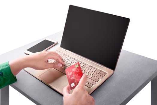 Hand holding credit card while using laptop with blank screen for copyspace. Online Shopping concept