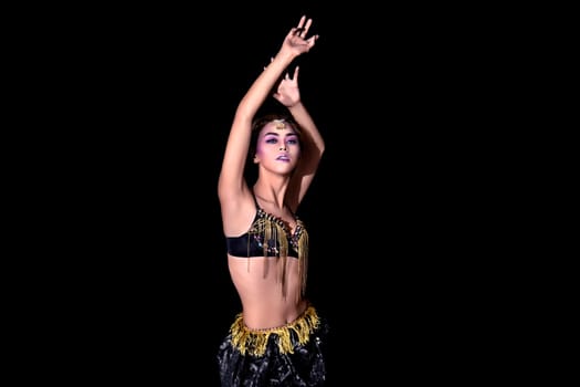 Exotic asian belly dancer in black suit and hands raised up on black background