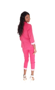 A portrait image of a African American woman in a pink.suit, smiling, from the back, isolated for white background.