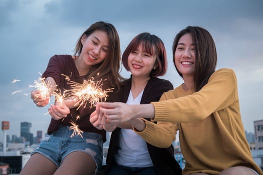 Youth friendship new year party concept. Group of asian friends having fun with sparklers at top roof.