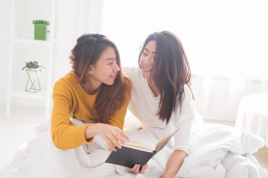 Lovely lesbian couple together concept. Couple of smiling young women sitting on the bed with happiness moment.