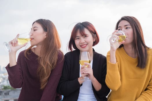 Youth friendship party concept. Group of asian friends drinking and having fun outdoor cheering at top roof.