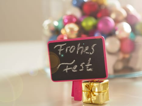 Christmas decoration on a table with the German words Merry Christmas on a small chalkboard, selective focus on foreground