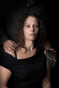 Abused woman victim of domestic violence, with husband hand holding a belt as a weapon.
