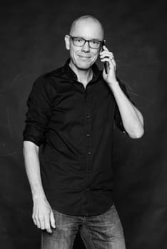 Studio recording of a man with a phone against a dark background
