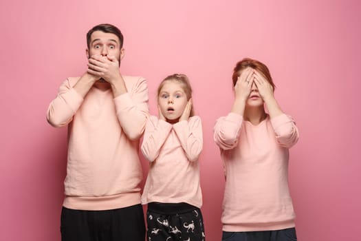 Surprised young family looking at camera on pink studio background. The concept of fear