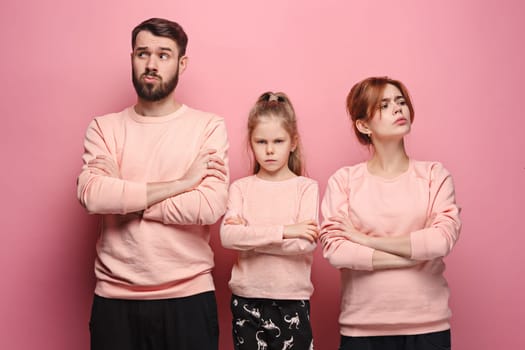 The sad and serious young family on pink studio background