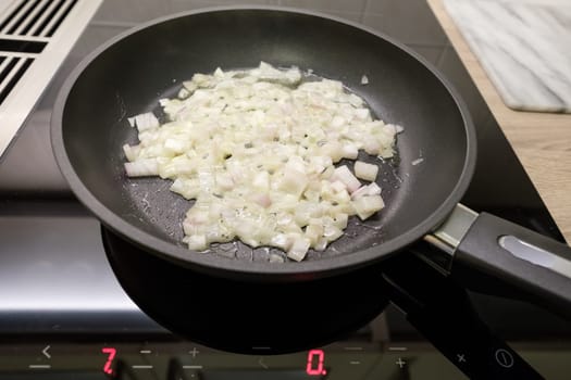 Fry onions in a coated pan on a stove with induction