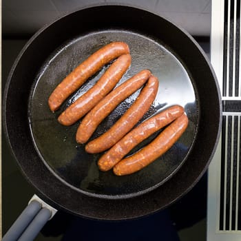 Top view of Merquez sausages in a pan on stove for induction