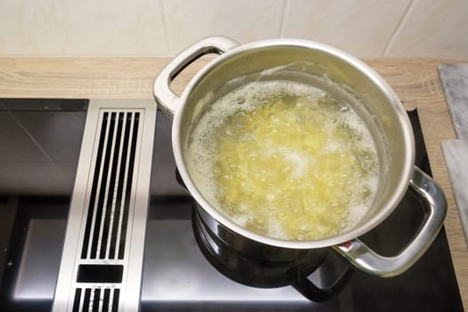 Boil potatoes in the water in the saucepan on stove with induction