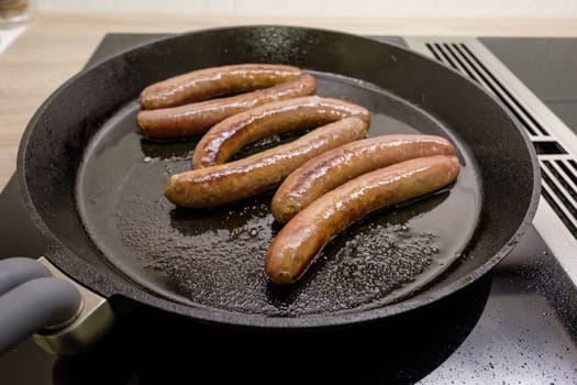 Merguez sausages fry in oil in a pan of cast iron on the stove