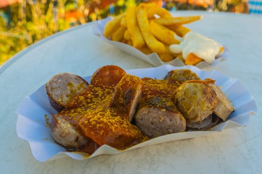 Delicious currywurst and fries on a paper plate