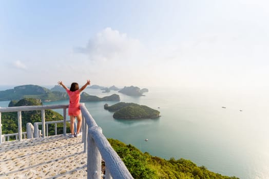 Woman tourist on the balcony is peak view point of Ko Wua Ta Lap island and beautiful nature landscape during sunrise over the sea in Mu Ko Ang Thong National Park, Surat Thani, Thailand