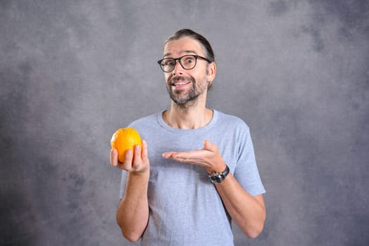 long haired young man with orange in front of gray background