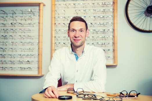 in optician shop- young dark haired man with new glasses