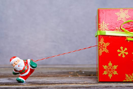 little Santa Claus pulling big red gift box