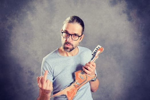 wild young man with cardboard guitar showing middle finger