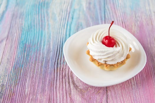 Tasty mini cake with cherry on a color gradient background