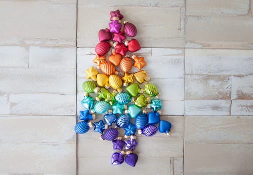 Christmas tree made of colorful Christmas tree balls on background made of wood