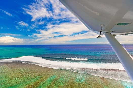 Aerial view of the coral reef. Plane wing on the foreground. Mauritius