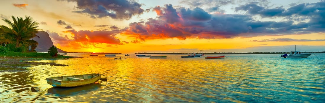 Fishing boat at sunset time. Le Morn Brabant on background. Mauritius. Panorama landscape