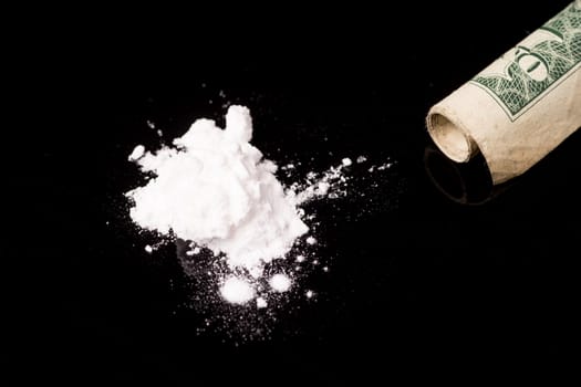 cocaine or other illegal drugs that are sniffed by means of a tube, isolated on black glossy background