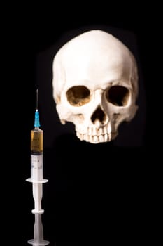 Syringe with brown liquid and blurry skull isolated on black background