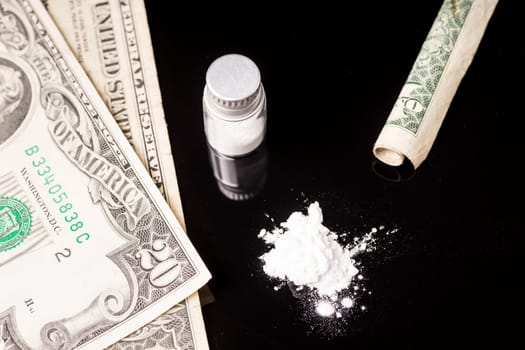cocaine or other illegal drugs that are sniffed by means of a tube, isolated on black glossy background