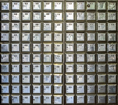 Wall full of rows of old shiny metal post office boxes
